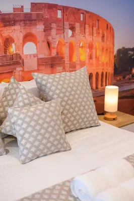 a bed with pillows in front of the coliseum at Luxury Suite-Metro Malatesta in Rome