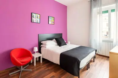 a purple bedroom with a bed and a red chair at San Giovanni Living House in Rome