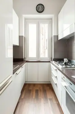 a kitchen with white cabinets and a clock on the wall at San Giovanni Living House in Rome