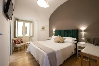 a bedroom with a large white bed and a chair at Maison Aurora in Rome