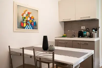 a kitchen with a table with chairs and a painting on the wall at Maison Aurora in Rome