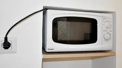 a white microwave sitting on a wooden shelf at Due passi dal cupolone - appartamento al centro in Rome