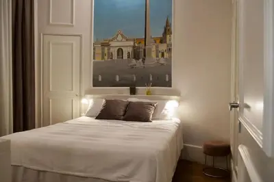 a bedroom with a white bed with a painting on the wall at Dimora Vantaggio in Rome