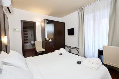 a hotel room with two white beds and a bathroom at Gemini Rooms in Rome