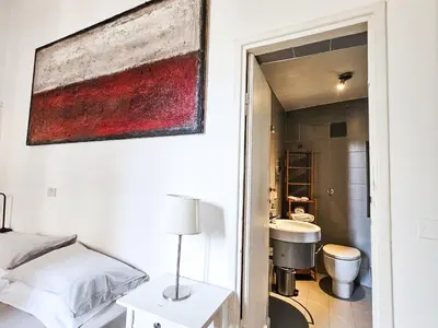 a bedroom with a bed and a bathroom with a sink at Titus House nelle vicinanze del Colosseo in Rome