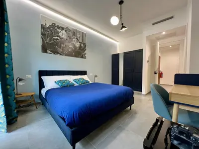 a bedroom with a blue bed and a desk at Alma Domus Feriae - Roma in Rome