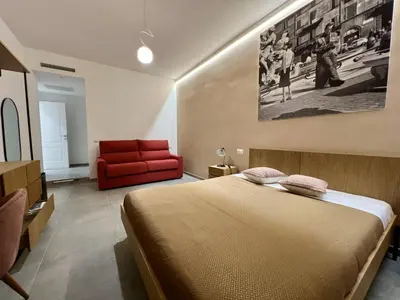 a bedroom with a bed and a red couch at Alma Domus Feriae - Roma in Rome