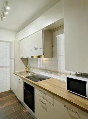 a kitchen with white cabinets and a black microwave at Martina al Colosseo in Rome
