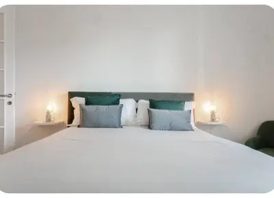 a bedroom with a large white bed with two lamps at Suite Guido Reni in Rome
