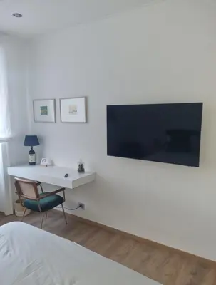 a bedroom with a desk and a television on a wall at Suite Guido Reni in Rome