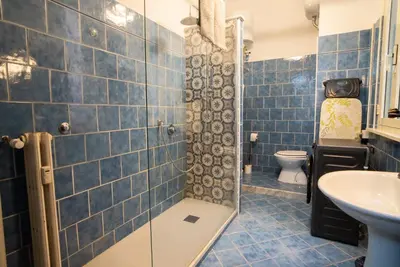 a blue tiled bathroom with a sink and a toilet at Optima mansio in Rome