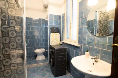 a blue tiled bathroom with a toilet and a sink at Optima mansio in Rome