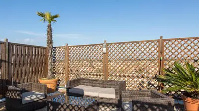 a patio with chairs and a table and a palm tree at Panorama Penthouse by Rental in Rome in Rome
