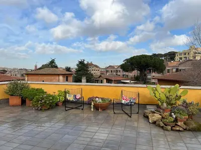 a patio with chairs and potted plants and a yellow wall at Loft in Garbatella in Garbatella