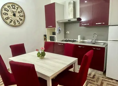 a kitchen with a table with red chairs and a clock at Dimora Sistina Roma in Rome