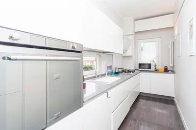a white kitchen with white cabinets and a sink at Elegant apartment metro A - by OpenRoma in Rome