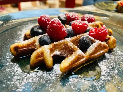 a plate with waffles and berries on it at Cloud 7 Roma Hotel in Rome