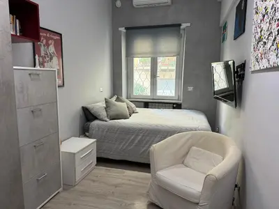 a small bedroom with a bed and a chair at Dolce Vita House - 10min walk to Vatican in Rome