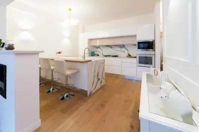 a kitchen with white cabinets and a wooden floor at Vatican Home 168 in Rome