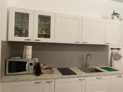 a kitchen with white cabinets and a sink and a microwave at Il diamante del Colosseo in Rome