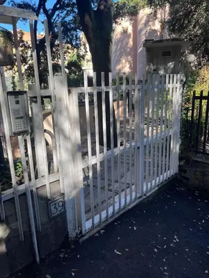 a white fence in front of a house with a tree at Sweet Home Cavalese, Cortina d'Ampezzo, Università Cattolica, Gemelli in Rome
