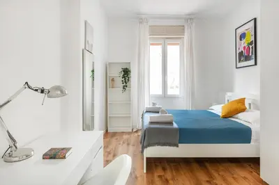 a white bedroom with a blue bed and a desk at Trieste Home! in Rome