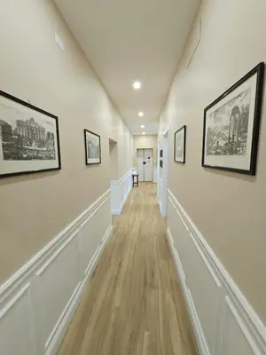 a hallway with white walls and wood floors and framed pictures at Linetta Charme House in Rome