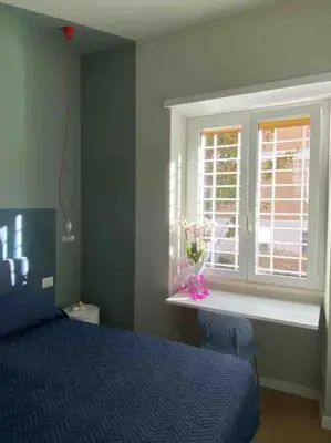 a bedroom with a blue bed and a window at Casa Anacapri in Rome