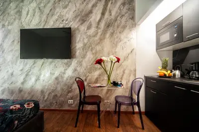 a kitchen with a table with chairs and a tv on a wall at farnese jacuzzi apartment in Rome