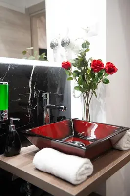 a red sink with a vase of roses on a counter at farnese jacuzzi apartment in Rome