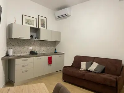 a living room with a couch and a kitchen at Condottieri's Hidden Home - Metro C direct to Colosseum in Rome