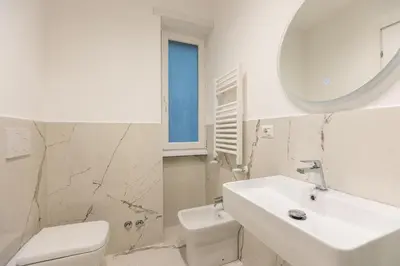 a white bathroom with a sink and a mirror at TRASTEVERE PALACE GUEST House in Rome