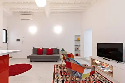 a white living room with a couch and a television at Suite Boschetto Holidays in Rome