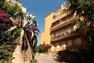 a palm tree in front of a building with flowers at Gozzadini Apartment in Rome