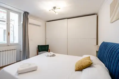 a bedroom with a white bed and a blue chair at Campo de Fiori - Casa Storica 4bdr con Terrazza in Rome