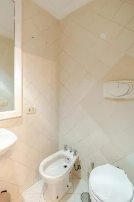 a white bathroom with a toilet and a sink at Campo de Fiori - Casa Storica 4bdr con Terrazza in Rome
