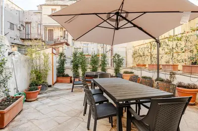 a wooden table with chairs and an umbrella on a patio at Campo de Fiori - Casa Storica 4bdr con Terrazza in Rome