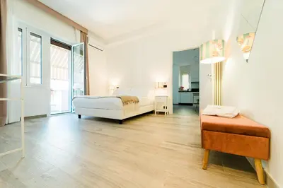 a white bedroom with a bed and a bench in it at Maison Pesca in Rome