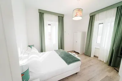 a bedroom with a white bed and green curtains at Maison Salvia in Rome