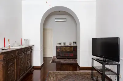 a living room with a flat screen tv and an archway at Via Veneto e La Dolce Vita in Rome