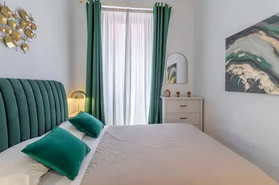 a bedroom with a large bed with green accents at 2 minutes from the Colosseum - Luxury apartment in Rome