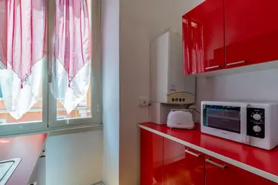 a kitchen with red cabinets and a microwave on a counter at 2 minutes from the Colosseum - Luxury apartment in Rome