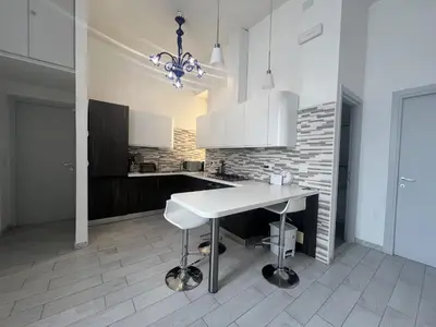 a white kitchen with a table and a counter at Stephany's Guesthouse in Rome