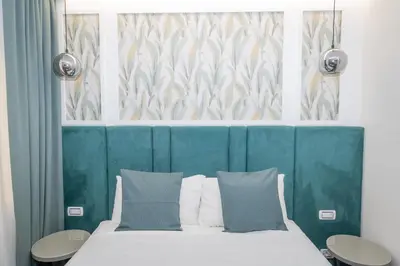 a bedroom with a bed with a blue headboard and two tables at La Genziana in Rome