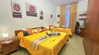 a hotel room with two beds with yellow sheets at A Casa Simpatia Vaticano in Rome