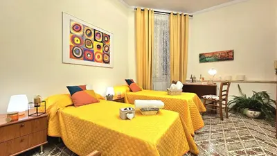a room with two beds with yellow sheets at A Casa Simpatia Vaticano in Rome