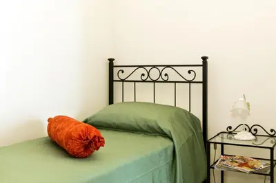 a bed with an orange pillow sitting on top of it at Il Bacio Holidayhouse BEST LOCATION FOR VISIT THE VATICAN in Rome