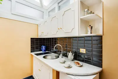 a kitchen with white cabinets and a sink at Spanish Steps Boutique Gold Apartment in Rome