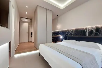 a bedroom with a large white bed and a hallway at Roma Suite Major in Rome