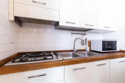 a white kitchen with a sink and a microwave at Sunny Charming 3 BDR, 3BATH Home in Rome